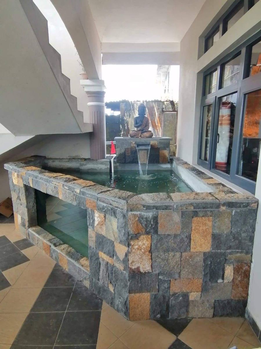Custom stone clad water feature and fish pond with a glass viewing panel